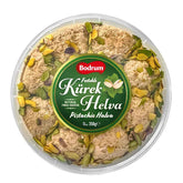 A 350g round plastic container of Bodrum Pistachio Kurek Halva, topped with premium pistachios and a central green label. Enjoy the rich, authentic taste of this sesame halva from Bodrum.